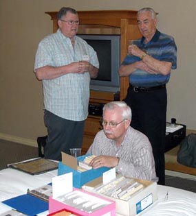 Jon Johnson kneels to the great bourse god
                in the hospitality suite as Peter Fralick and Cec Coutts look on